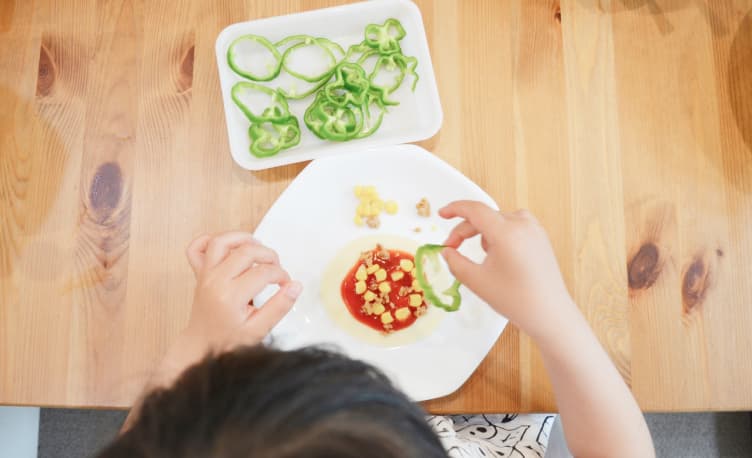 スライスされた野菜を手にとる園児