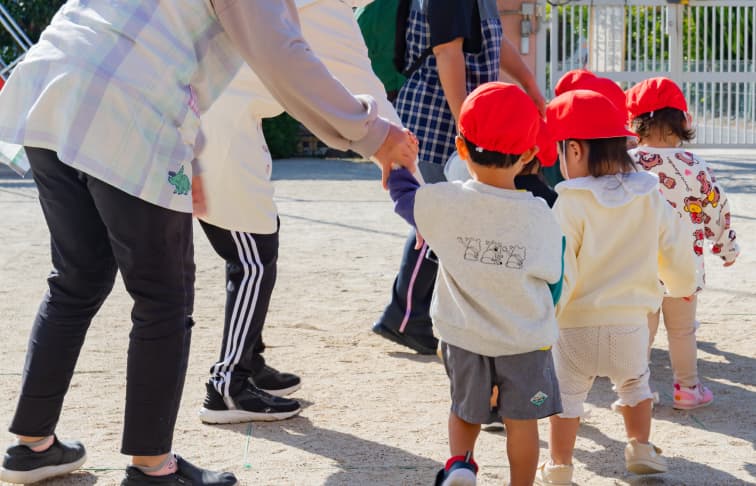 先生たちと手を繋いで歩く園児たち